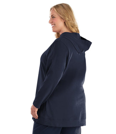 Plus size woman, facing back left, wearing JunoActive plus size Legacy Cotton Casual Pullover Hoodie in the color Navy. She is wearing JunoActive Plus Size Leggings in the color Navy.
