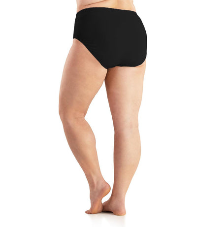 Bottom half of plus sized woman, back view, wearing JunoActive Junowear Cotton Stretch Classic Brief in black. This brief fits to the waistline with conservative leg opening.