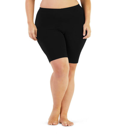 Bottom half of plus sized woman, front view, wearing JunoActive Stretch Naturals Bike Shorts in color black. Bottom hem is a few inches above the knee. 