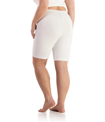 Bottom half of plus sized woman, back view, wearing JunoActive Stretch Naturals Bike Shorts in color white. Bottom hem is a few inches above the knee.