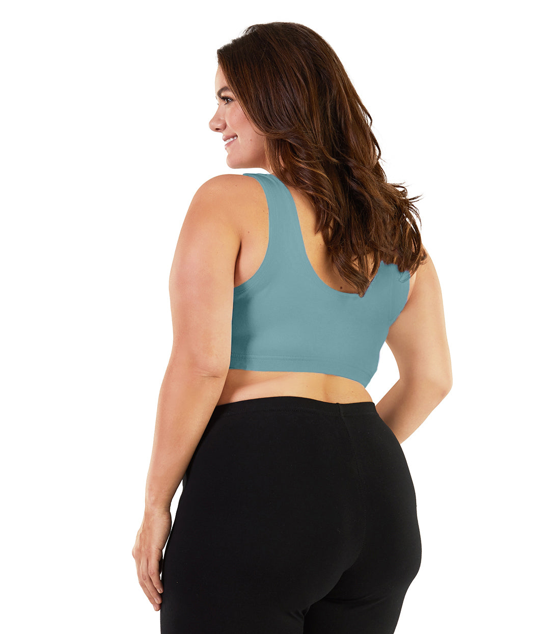 Plus size woman, facing back, wearing JunoActive plus size Stretch Naturals Scoop Neck Bra in soft green. The woman is wearing black plus size JunoActive leggings. Her arms fall naturally to her side. 