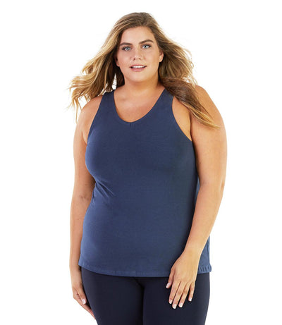 Plus size woman, facing front, wearing JunoActive plus size Stretch Naturals Tank in Denim Blue. The woman is wearing a pair of Navy Blue JunoActive leggings.