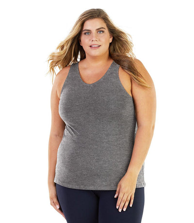 Plus size woman, facing front, wearing JunoActive plus size Stretch Naturals Tank in Heather Grey. The woman is wearing a pair of Navy Blue JunoActive leggings. 