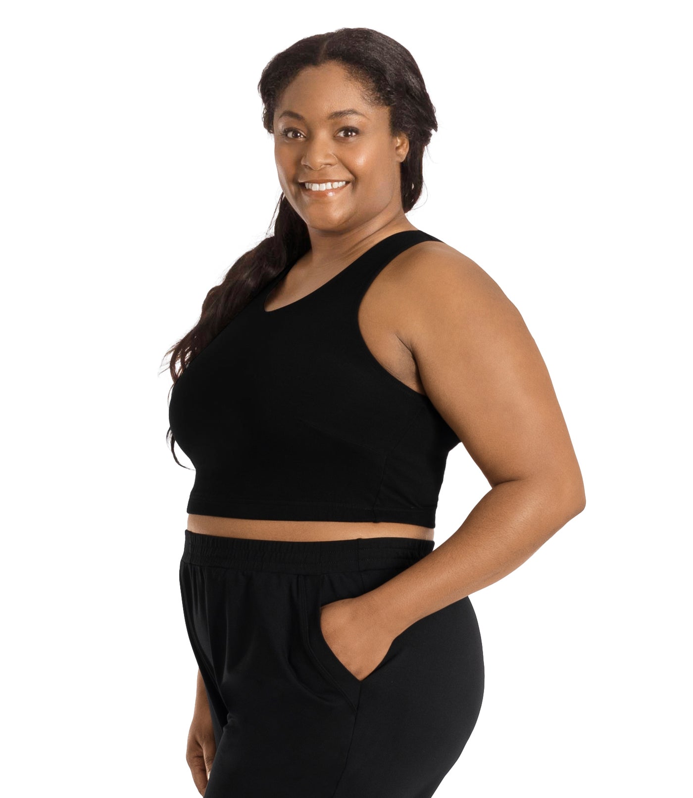  Plus size woman, facing right front side, wearing a black JunoActive Stretch naturals full fit plus size bra. Featuring a v-neck and side bust darts for a full fit. She is also wearing black JunoActive plus size pants.