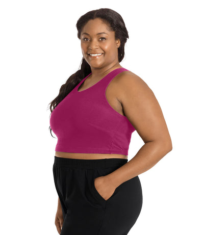 Plus size woman, facing right front side, wearing a merlot colored JunoActive Stretch naturals full fit plus size bra. Featuring a v-neck and side bust darts for a full fit. She is also wearing black JunoActive plus size pants.
