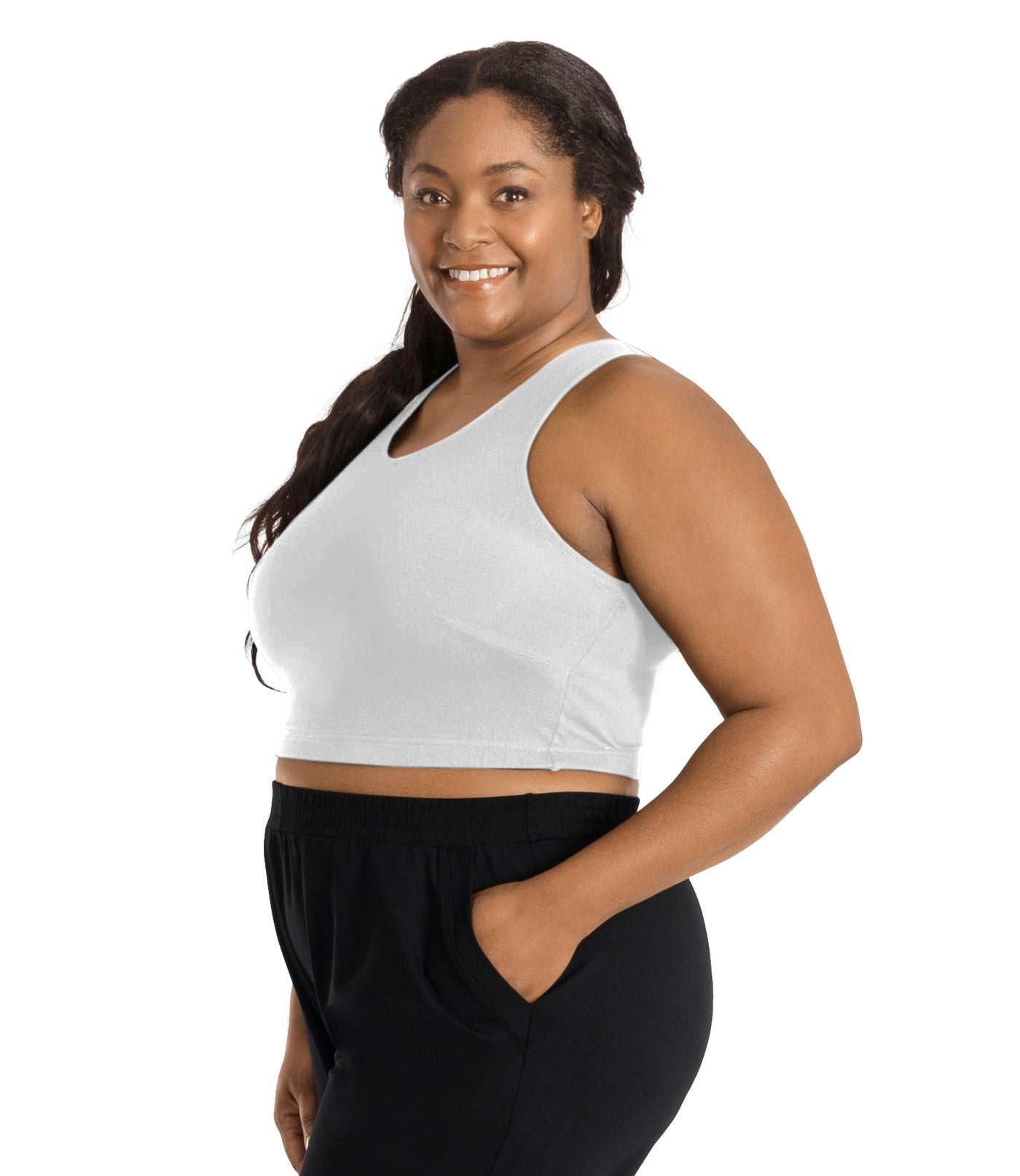 Plus size woman, facing right front side, wearing a white JunoActive Stretch naturals full fit plus size bra. Featuring a v-neck and side bust darts for a full fit. She is also wearing black JunoActive plus size pants.