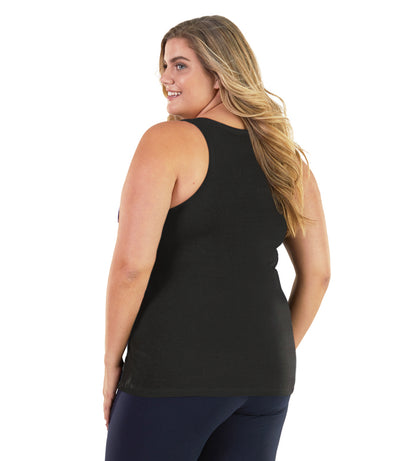 Plus size model, facing back, wearing Stretch Naturals V-Neck Tank in Black. Arms fall naturally by her side. She is also wearing JunoActive plus-size leggings in navy.