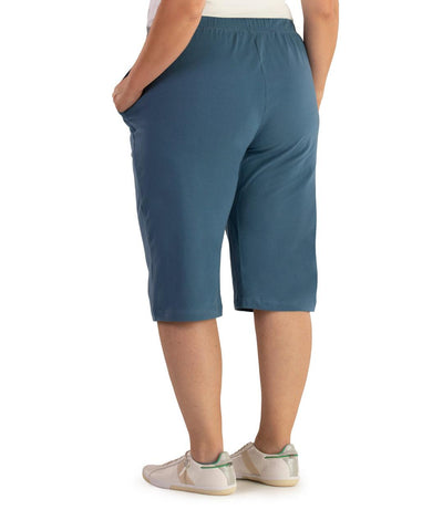 Bottom half of plus sized woman, back view, wearing JunoActive Stretch Naturals Bermuda Shorts in color denim blue. Bottom hem is at the knee.