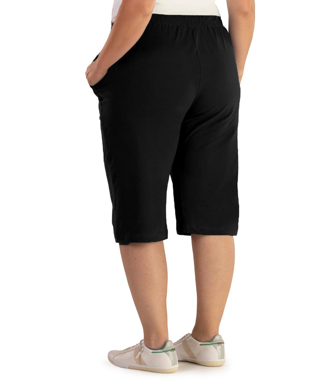 Bottom half of plus sized woman, back view, wearing JunoActive Stretch Naturals Bermuda Shorts in color black. Bottom hem is at the knee.
