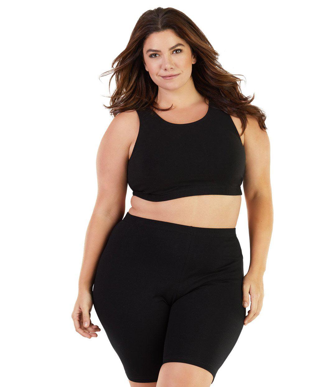 Plus size woman, facing front, wearing JunoActive plus size Stretch Naturals Crossback Bra Top in Black. The woman is wearing a pair of Black JunoActive fitted boxers.