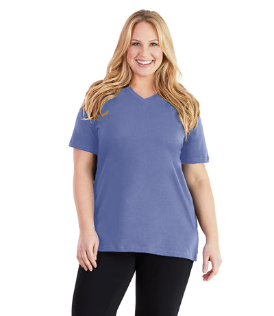 Plus size woman, facing front, wearing JunoActive plus size Stretch Naturals V-Neck in the color Cornflower Blue. She is wearing JunoActive Plus Size Leggings in the color black. 