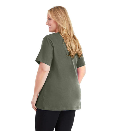 Plus size woman, facing back and looking left, wearing JunoActive plus size Stretch Naturals V-Neck in the color Moss Green. She is wearing JunoActive Plus Size Leggings in the color black.