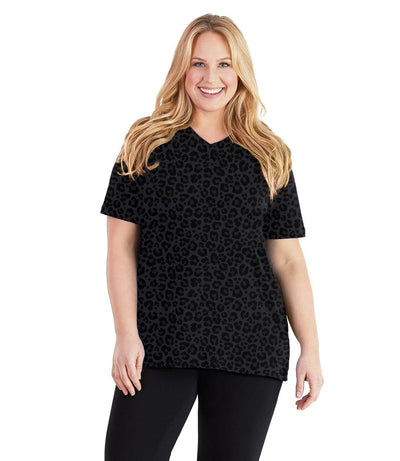Plus size woman, facing front, wearing JunoActive plus size Stretch Naturals V-Neck in the color Deep Leopard Print. She is wearing JunoActive Plus Size Leggings in the color black. 
