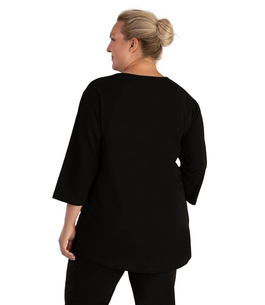 Plus size woman, facing back looking left, wearing JunoActive plus size Stretch Naturals Scoop Neck ¾ Sleeve Top in the color Black. She is wearing JunoActive Plus Size Leggings in the color Black.
