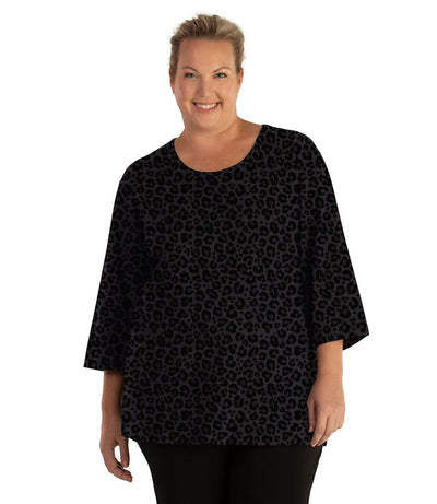 Plus size woman, facing front, wearing JunoActive plus size Stretch Naturals Scoop Neck ¾ Sleeve Top in the color Deep Leopard Print. She is wearing JunoActive Plus Size Leggings in the color Black.