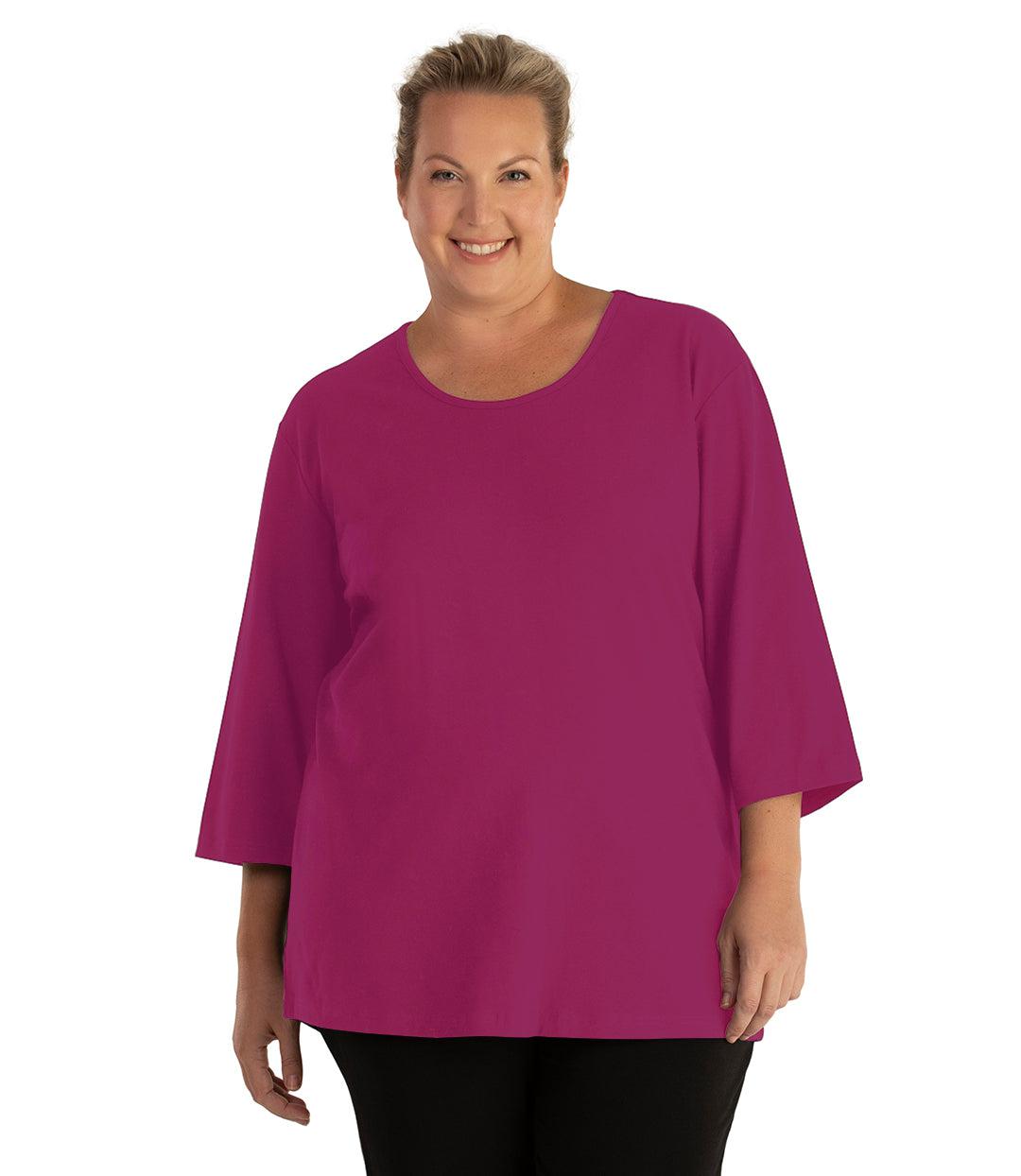 Plus size woman, facing front, wearing JunoActive plus size Stretch Naturals Scoop Neck ¾ Sleeve Top in the color Merlot. She is wearing JunoActive Plus Size Leggings in the color Black.