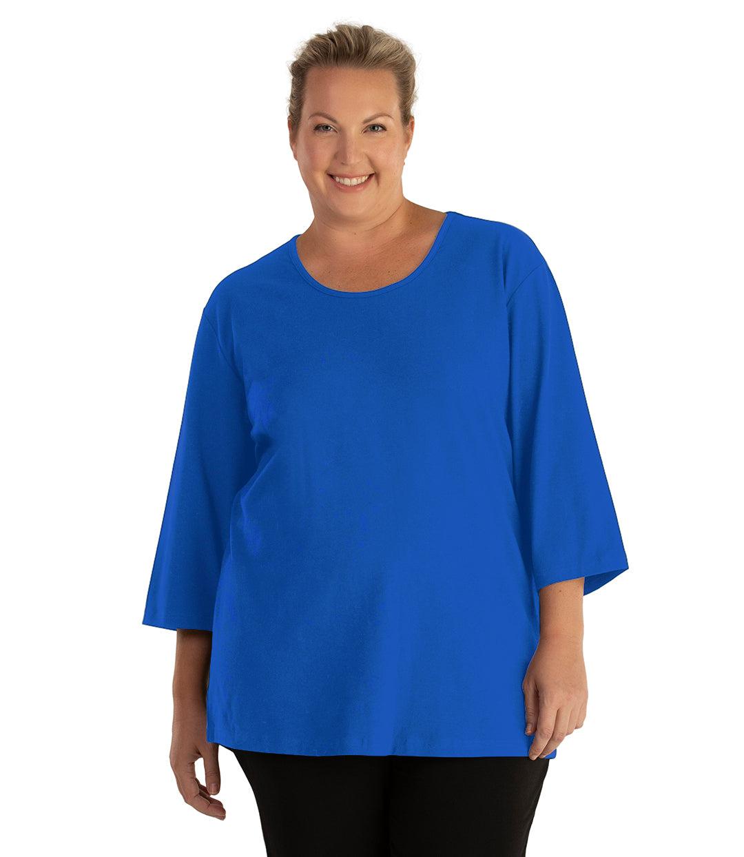 Plus size woman, facing front, wearing JunoActive plus size Stretch Naturals Scoop Neck ¾ Sleeve Top in the color Vivid Blue. She is wearing JunoActive Plus Size Leggings in the color Black.