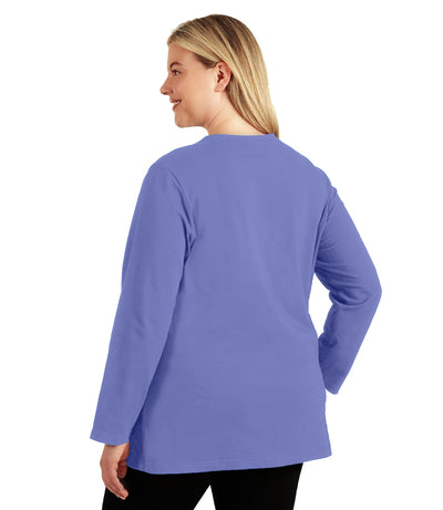 Plus size woman, facing back looking left, wearing JunoActive plus size Stretch Naturals Long Sleeve V-Neck Top in the color Cornflower Bluel. She is wearing JunoActive Plus Size Leggings in the color Black.