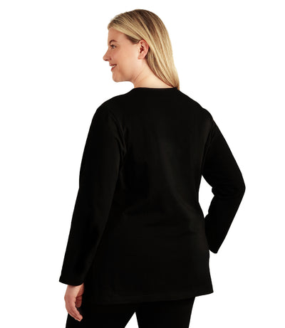 Plus size woman, facing back looking left, wearing JunoActive plus size Stretch Naturals Long Sleeve V-Neck Top in the color Black. She is wearing JunoActive Plus Size Leggings in the color Black.