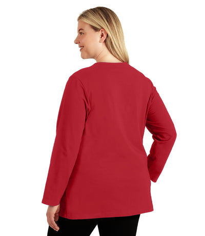 Plus size woman, facing back looking left, wearing JunoActive plus size Stretch Naturals Long Sleeve V-Neck Top in the color Lucky Red. She is wearing JunoActive Plus Size Leggings in the color Black.