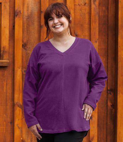 Plus-size model, facing forward, wearing JunoActive's Mavie Drop Shoulder V-neck Tunic in Magenta Purple.