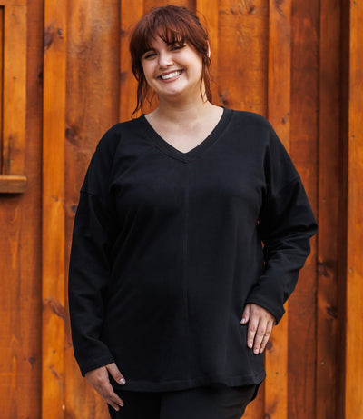 Plus-size women, facing front, wearing Mavie Drop Shoulder V-Neck Tunic in color black.