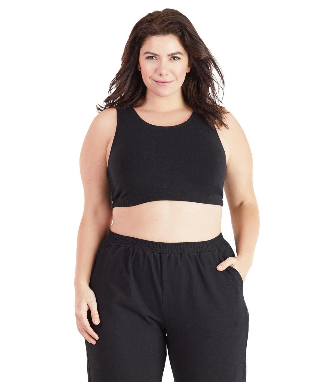 Plus size woman, facing front, wearing JunoActive plus size Stretch Naturals Scoop Neck Bra in black. The woman is wearing black plus size JunoActive loose fit leggings. Her right arm falls naturally to her side, her left arm is in the legging pocket. 