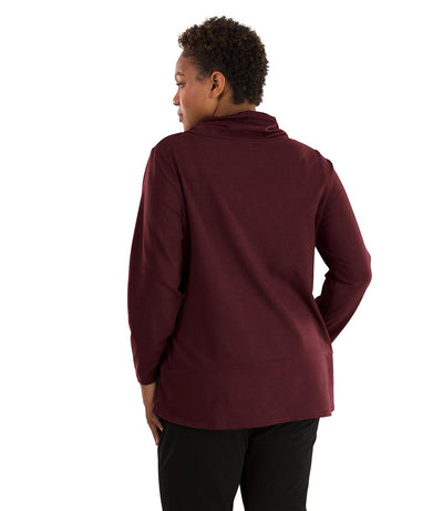 Plus size woman, facing back looking left, wearing JunoActive plus size Stretch Naturals Cowl Top in the color Elderberry. She is wearing JunoActive Plus Size Leggings in the color Black.