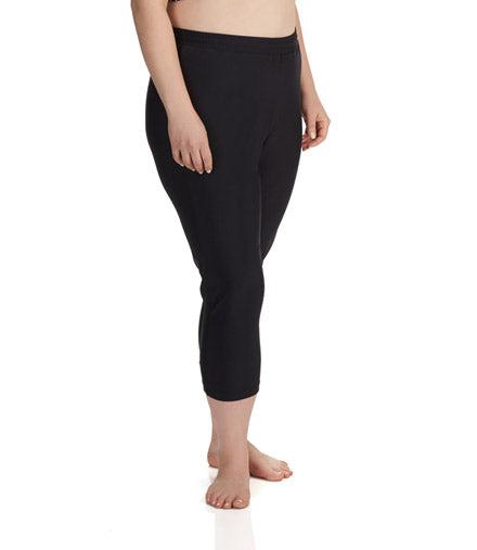 Plus size model, facing side, wearing QuikEnergy Capris in solid black. Length hitting mid-shin. 