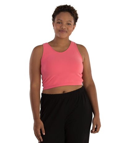 Plus size woman, facing front, wearing JunoActive plus size Supplex Long-Line V-Neck Bra top in Pink. The woman is wearing black JunoActive plus size leggings. 