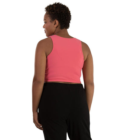 Plus size woman, facing back, wearing JunoActive plus size Supplex Long-Line V-Neck Bra top in Pink. The woman is wearing black JunoActive plus size leggings. 