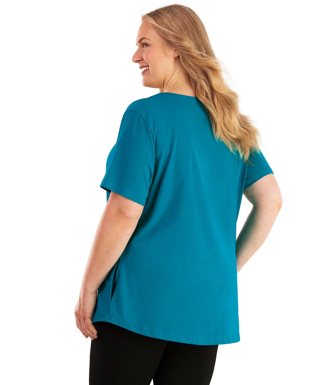 Plus size woman, facing back looking left, wearing JunoActive plus size Stretch Naturals Lite Pocket Tee in the color Teal. Her right hand is in the shirt pocket by her hip, her left arm is naturally at her side. She is wearing JunoActive Plus Size Leggings in the color Black.