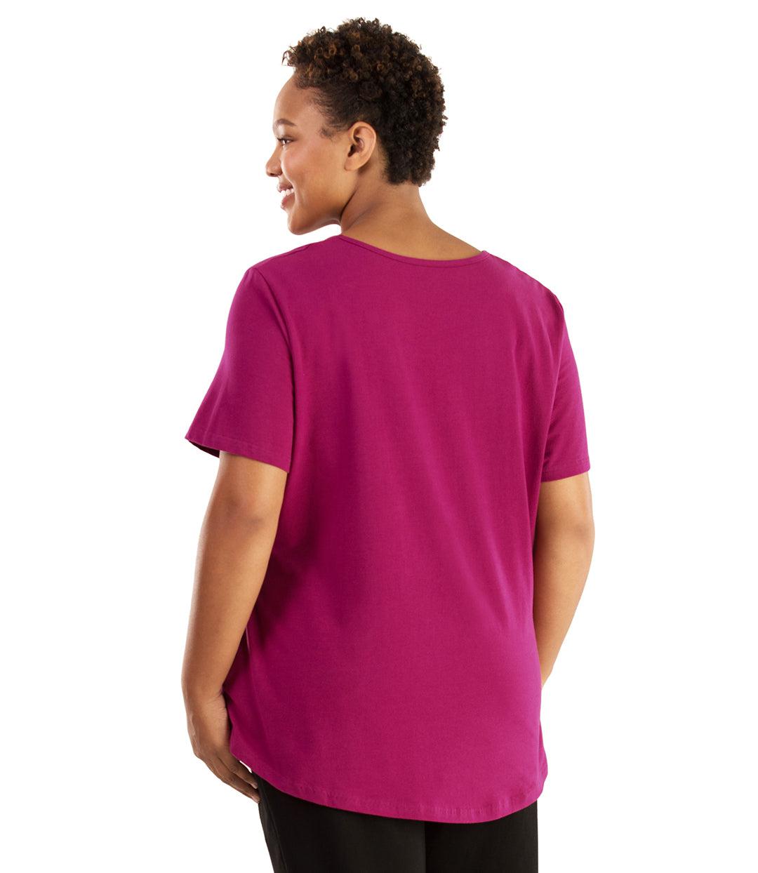 Plus size woman, facing back looking left, wearing JunoActive plus size Stretch Naturals Lite Pocket Tee in the color Magenta. Her right hand is in the shirt pocket by her hip, her left arm is naturally at her side. She is wearing JunoActive Plus Size Leggings in the color Black.