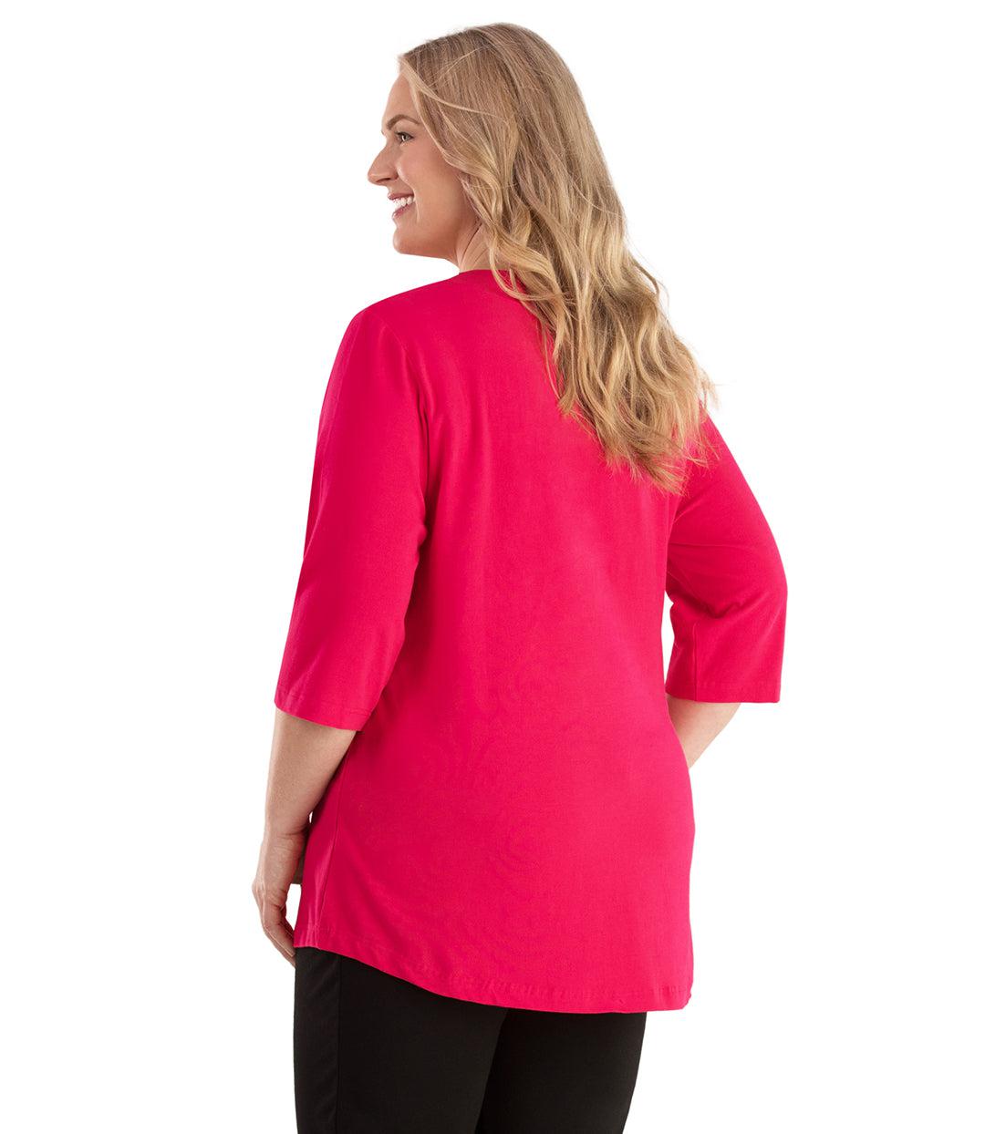 Plus size woman, facing back looking left, wearing JunoActive plus size Stretch Naturals Vee NeckTee in the color Pink. She is wearing JunoActive Plus Size Leggings in the color Black. 