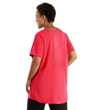 Plus size woman, facing front, wearing JunoActive plus size Stretch Naturals Lite Swing Top in the color Pink. She is wearing JunoActive Plus Size Leggings in the color black.