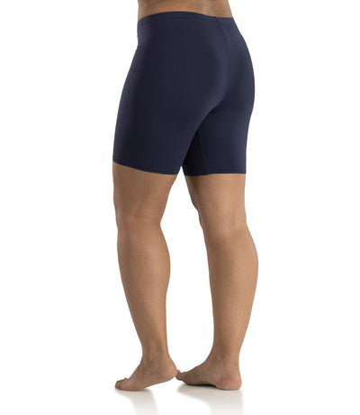 Bottom half of plus sized woman, back view, wearing JunoActive Junowear Hush Boxer Brief in navy. This fitted boxer fits to the waistline and leg opening is a few inches above the knee.